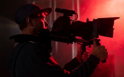 a man holding a camera in front of a red light