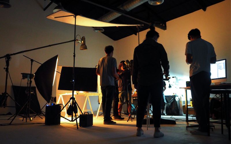 a group of people in a well-lit studio, surrounded by professional equipment and lighting setup